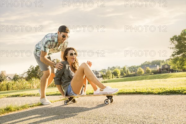 Smiling couple with skateboard in park