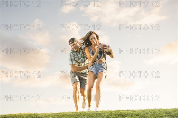 Smiling couple running on lawn with ball