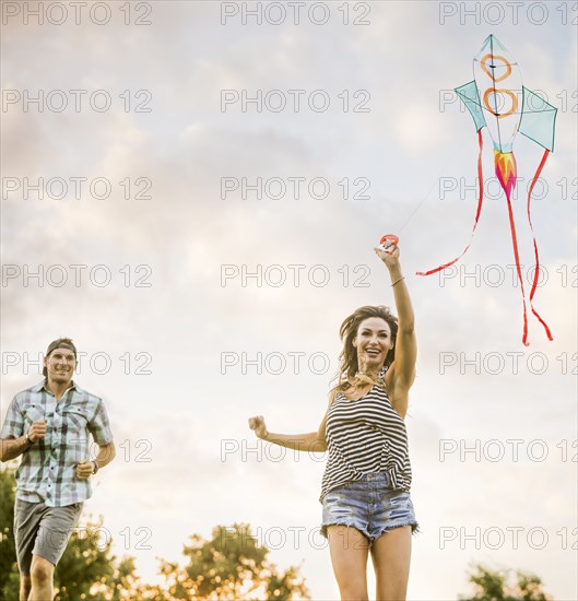 Smiling couple flying kite in park