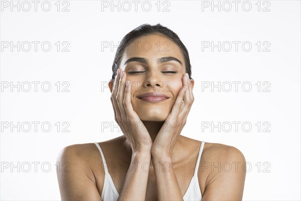 Portrait of young woman with eyes closed doing face massage