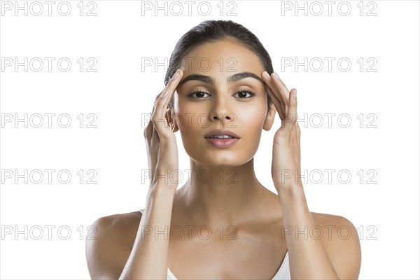 Portrait of serious young woman doing face massage