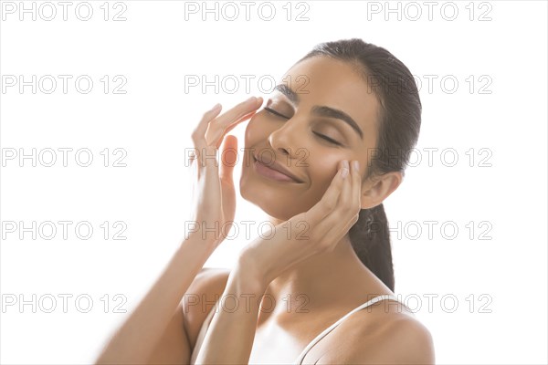 Portrait of smiling young woman doing face massage