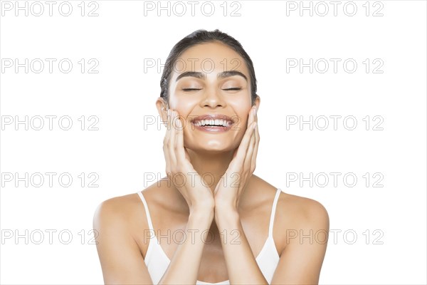Portrait of young woman with closed eyes doing facial massage