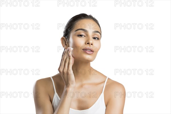 Portrait of young woman applying face cream