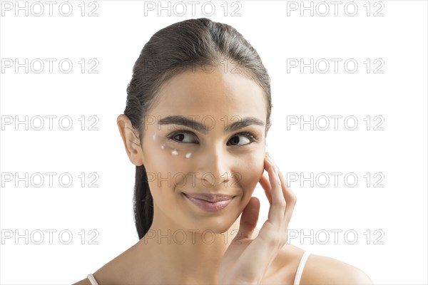 Portrait of smiling young woman applying face cream
