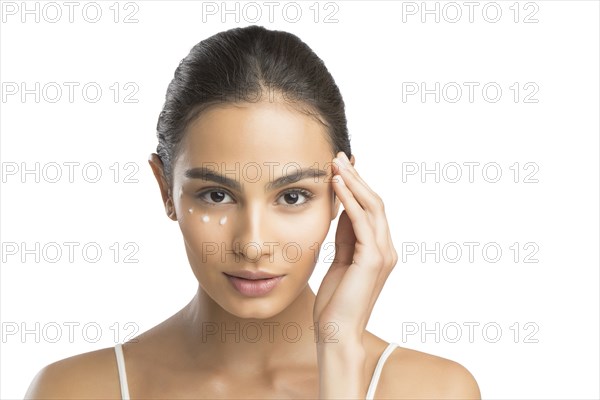 Portrait of serious young woman applying face cream