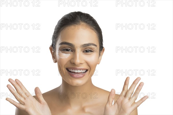 Portrait of smiling young woman applying face cream