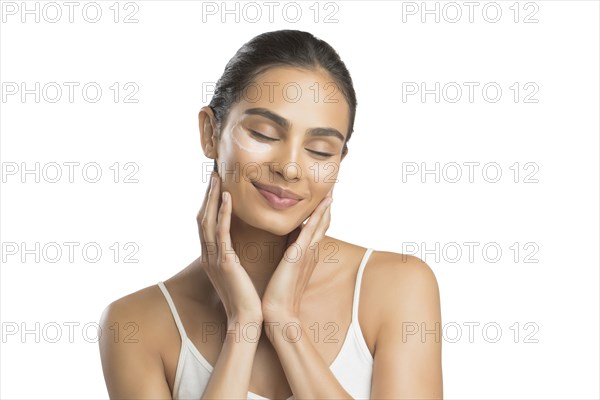 Portrait of smiling young woman applying face cream