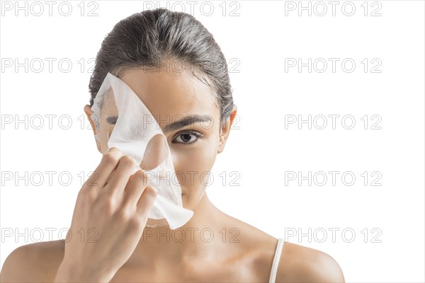 Portrait of young woman removing face mask