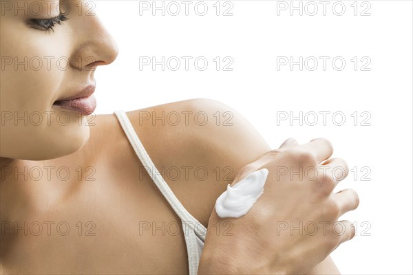 Portrait of young woman with face cream on hand