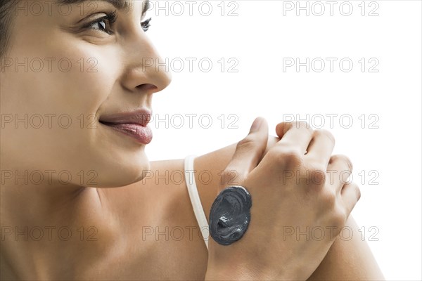 Portrait of young woman applying clay mask