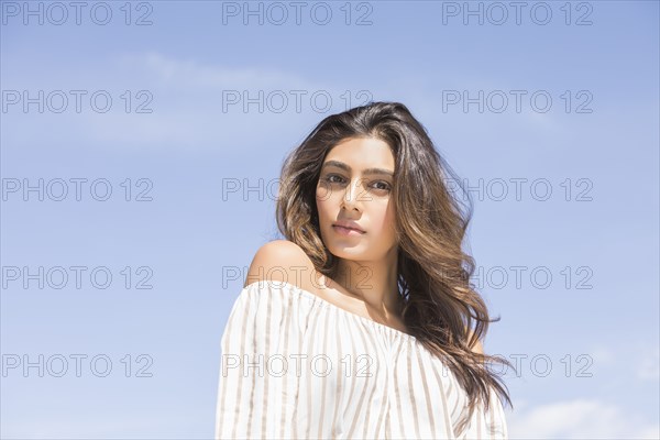 Portrait of serious young woman against clear sky