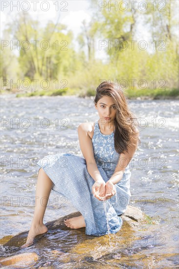 Portrait of young woman in long dress by river