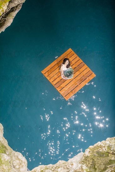 Aerial view of woman sitting on wooden raft