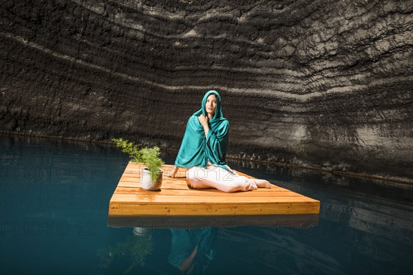 Woman sitting on wooden raft in cenote