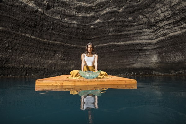 Woman sitting on wooden raft in cenote