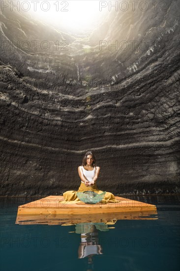 Woman sitting on wooden raft in cenote