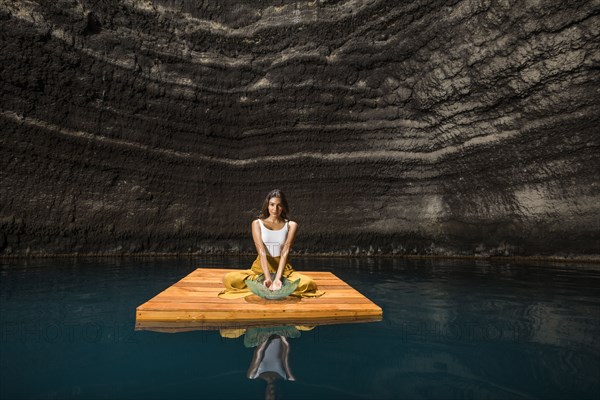 Woman sitting on wooden raft in cenote