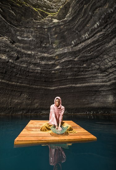 Woman sitting on wooden raft in cenote