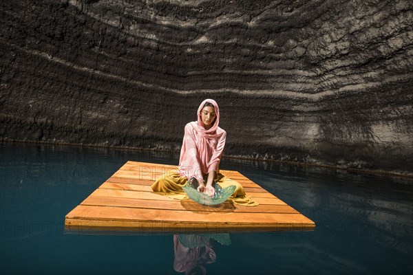 Woman sitting on wooden raft in cenote