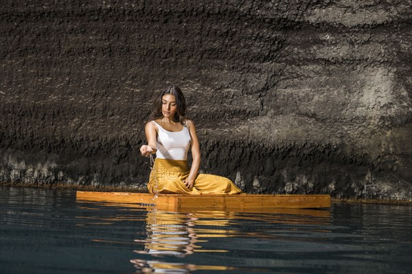 Woman sitting on wooden raft in cenote