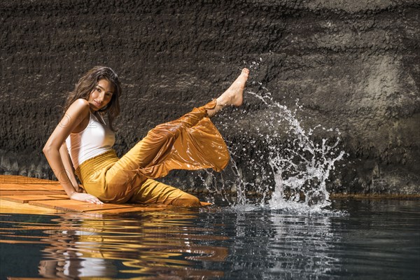 Beautiful woman splashing water on wooden raft in cenote