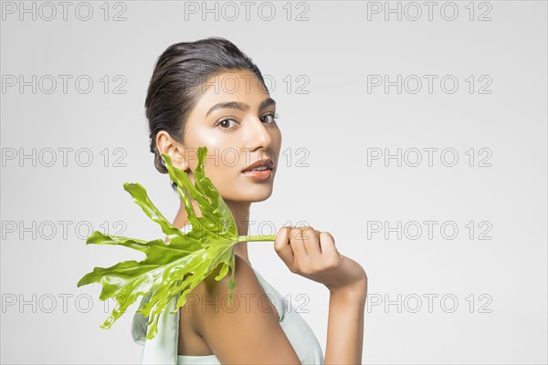 Studio portrait of beautiful woman with leaf