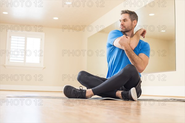 Man sitting on floor and stretching in dance studio