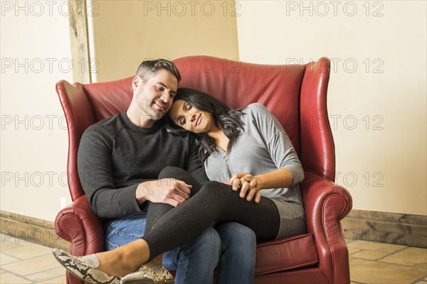 Happy couple sitting on large armchair