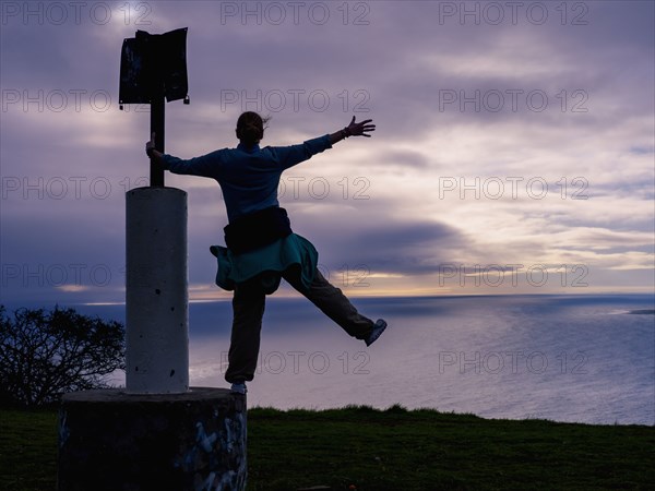 Woman standing on sign post on sea coast