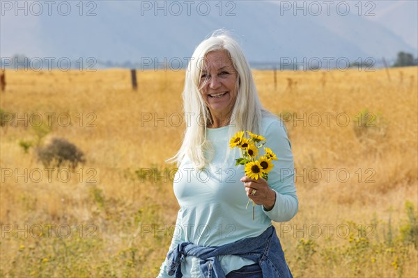 Portrait of senior woman holding bunch of sunflowers