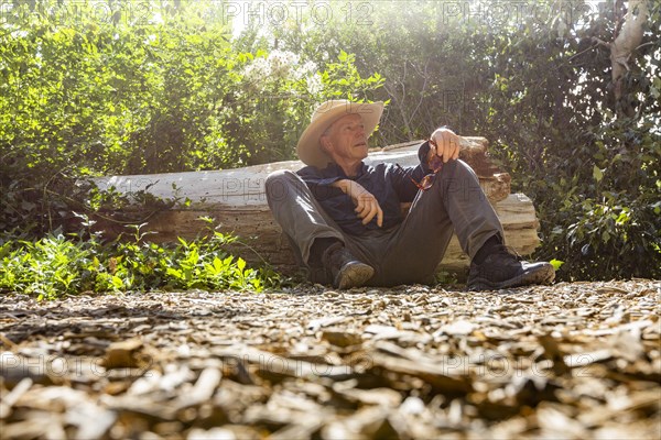 Senior man resting next to fallen tree