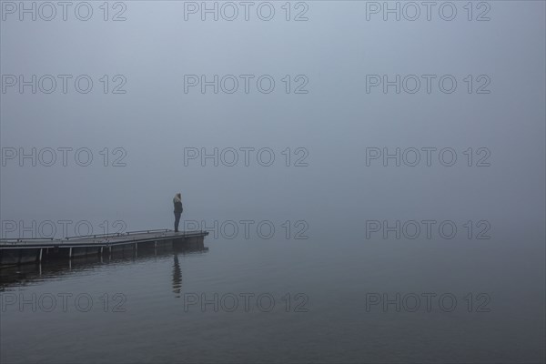 Woman standing on jetty in morning by lake