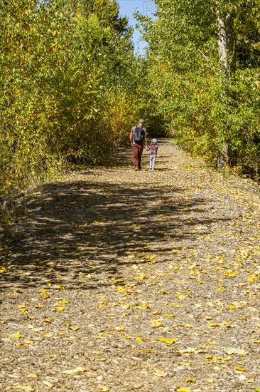 Father and daughter walk rural path in fall