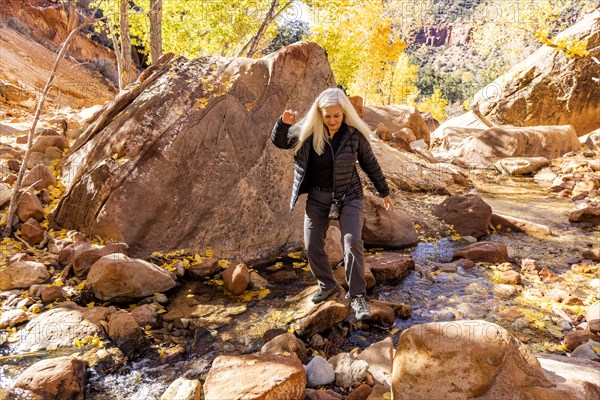 Senior female hiker crossing creek