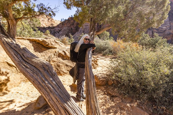 Senior female hiker hugging tree