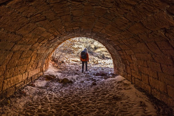 Female hiker walking through tunnel
