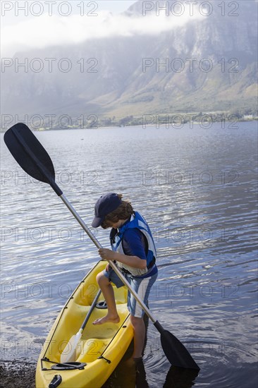 Boy entering kayak in lagoon
