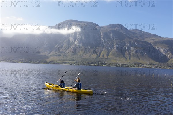 Boy and teenage girl kayaking in lagoon