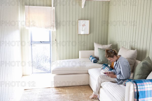 Teenage girl sitting on sofa and using phone