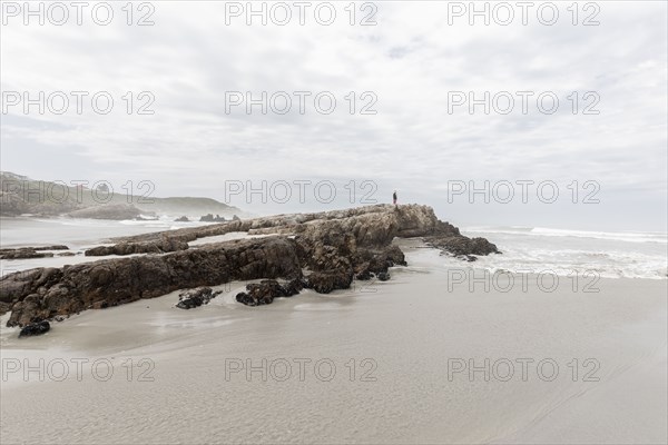 Boy standing on cliff on Voelklip Beach