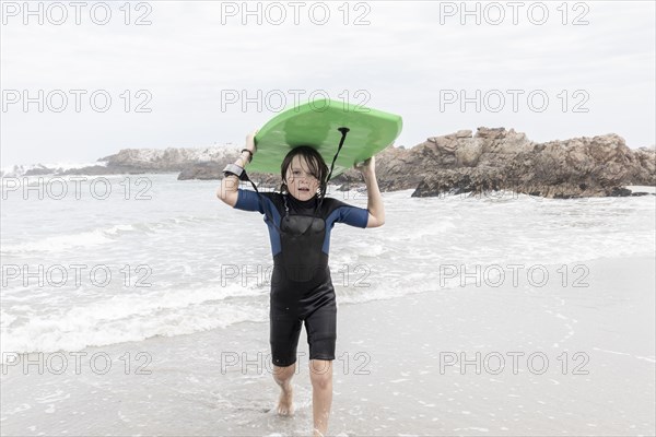 Boy carrying bodyboard on Voelklip beach