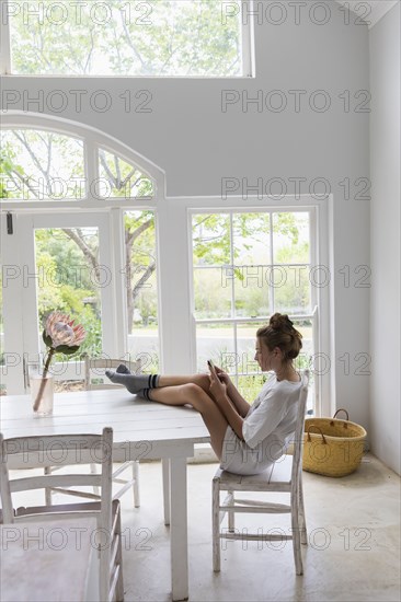 Teenage girl using smart phone in dining room