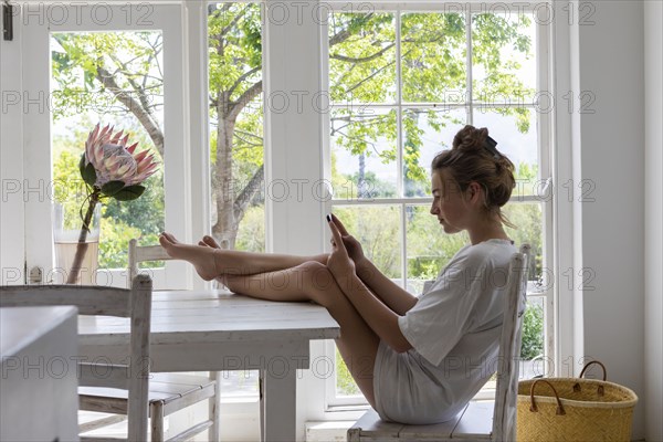 Teenage girl using smart phone in dining room