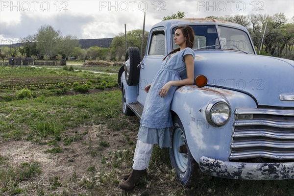 Young woman leaning on vintage car