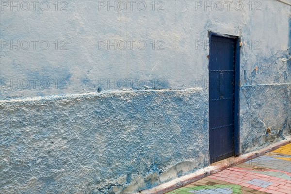 Colorful blue walls and old door in alleyway in medina