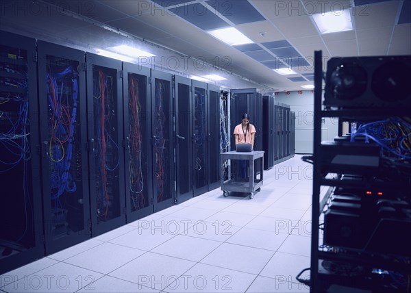 Female technician using laptop in server room