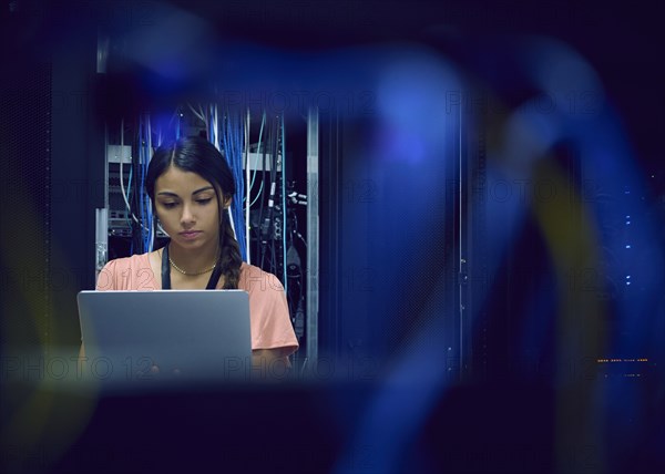 Female technician using laptop in server room