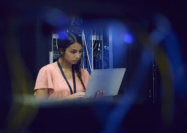 Female technician using laptop in server room