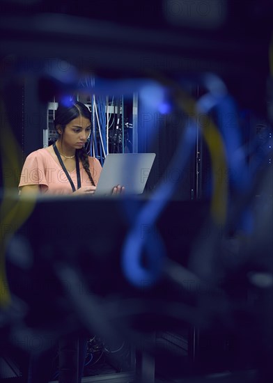 Female technician using laptop in server room